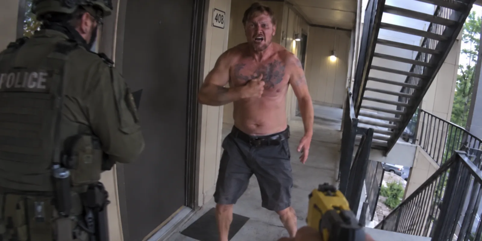 Officer point of view drawing a Taser on an aggressive man in an apartment doorway